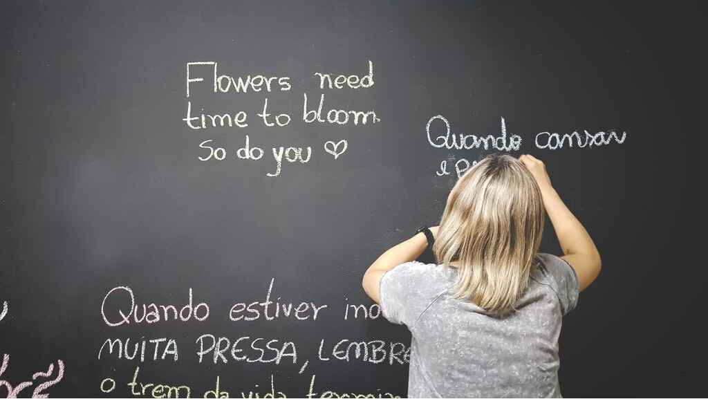 A blond haired child writes in a foreign language on a blackboard