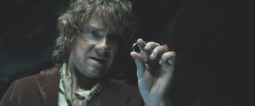Still from the Hobbit movie, showing Bilbo holding up the ring thoughtfully.