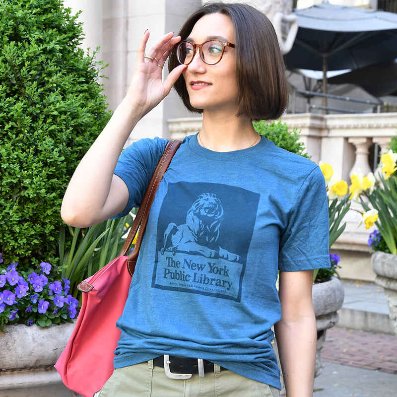 Woman wearing a blue NYPL t-shirt that shows a vintage lion design