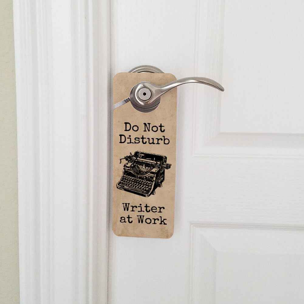 A door sign over a door handle, reading 'Do not disturb: Writer at work'