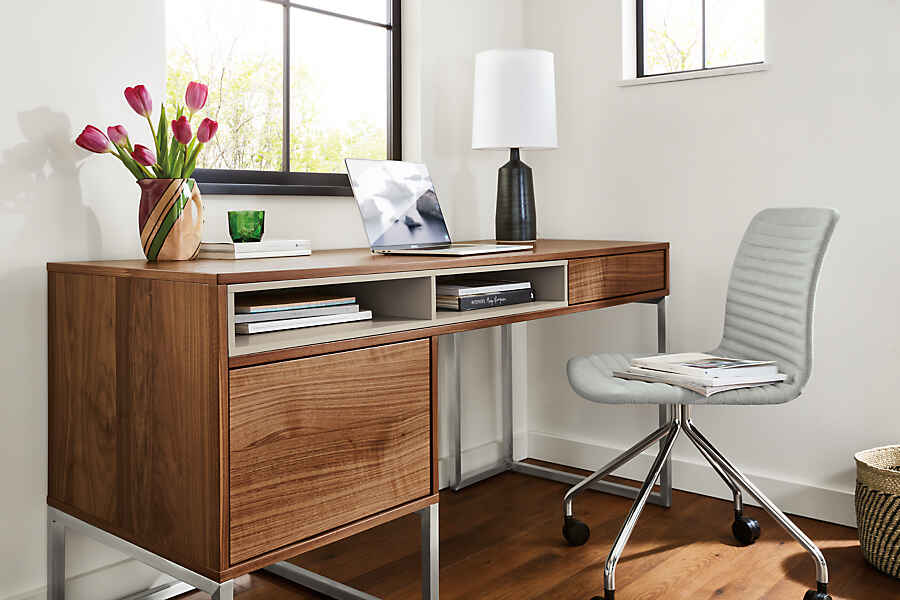 A sleek and modern wooden desk, next to an office chair and plant